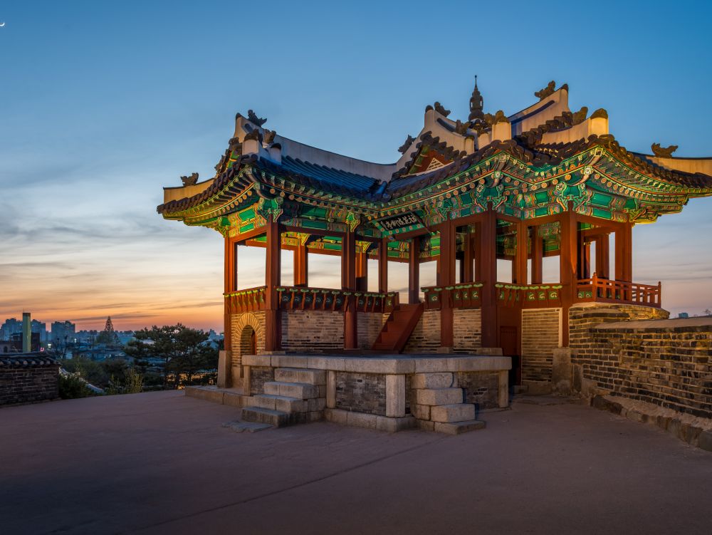 A watchtower at Hwaseong Fortress lit up at sunset in Suwon, South Korea.