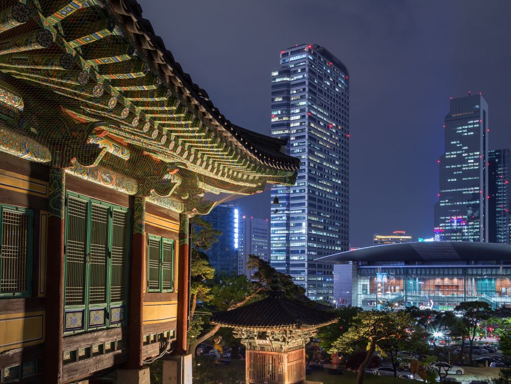 Ornate building at the Bongeunsa Temple and view of Gangnam in Seoul, South Korea at night.