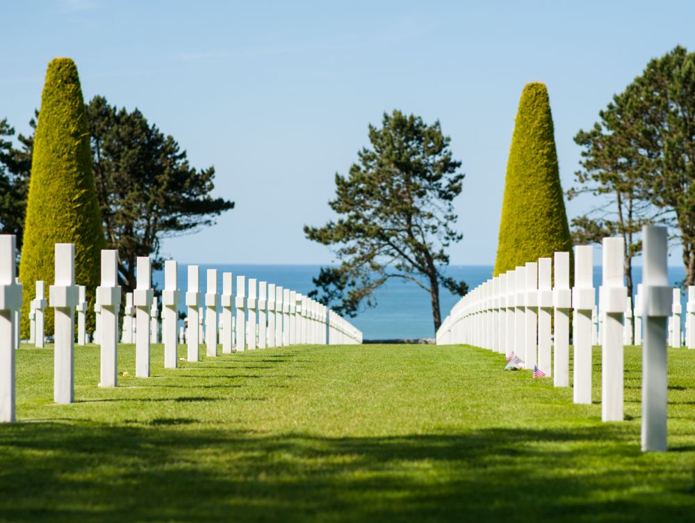 Alignement de croix dans le cimetière militaire de Colleville-sur-Mer, Normandie, France. Avec la mer et des arbres en arrière-plan.