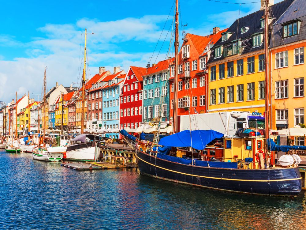 Scenic summer view of Nyhavn pier with color buildings, ships, yachts and other boats in the Old Town of Copenhagen, Denmark