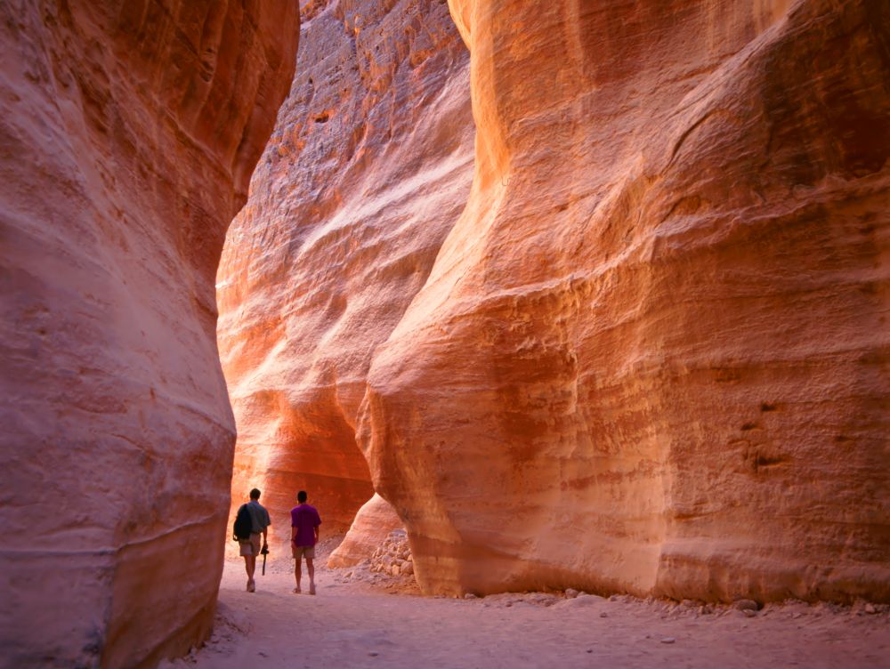 The Siq, the narrow slot-canyon that serves as the entrance passage to the hidden city of Petra, Jordan, seen here with tourists walking.This is an UNESCO World Heritage Site