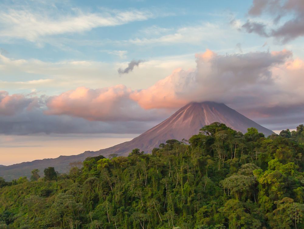 Arenal Volcano at Sunrise in Costa Rica, as the sun reflects on the newly formed clouds