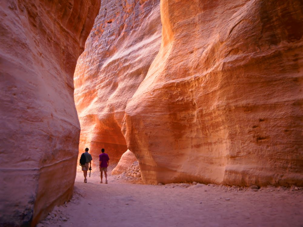 The Siq, the narrow slot-canyon that serves as the entrance passage to the hidden city of Petra, Jordan, seen here with tourists walking.This is an UNESCO World Heritage Site