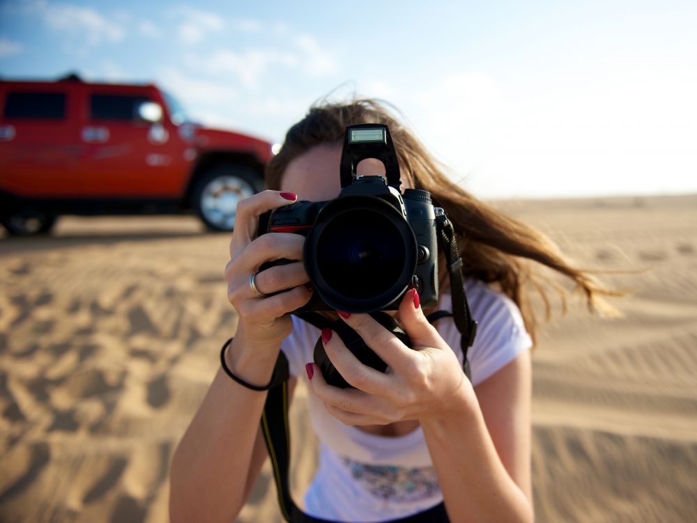 Jeune femme prenant une photo dans le désert de Dubai